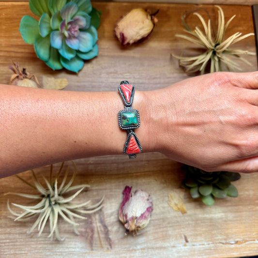 Handcrafted sterling silver cuff by MJ featuring a square green turquoise stone accented by red spiny oyster teardrop stones.