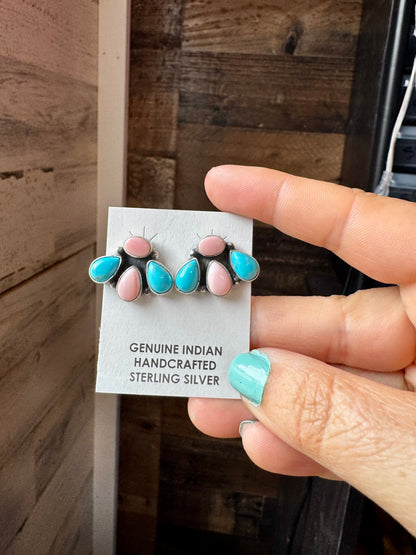 Handcrafted sterling silver stud earrings featuring genuine Kingman turquoise and pink conch stones. Stamped by artist Marcella James. Made in the USA. Each pair is naturally unique. Curated by The Bijoux FAB.