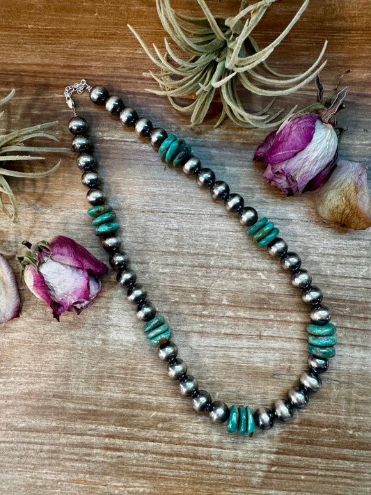 From our exclusive NFR Collection, this handcrafted necklace by The Bijoux FAB captures bold Western luxury. It features 12mm sterling silver pearls paired with a stunning 16mm green turquoise rondelle centerpiece. The turquoise shows natural variation in color and matrix, giving each necklace its own unique personality. Measuring 21.5 inches long plus extender, it’s finished with a sterling silver clasp and findings for timeless durability and shine. Only one was made — a true collector’s statement piece.
